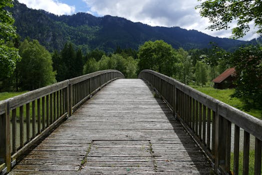Über uns A serene wooden bridge amidst lush greenery and mountains, perfect for a peaceful nature walk.